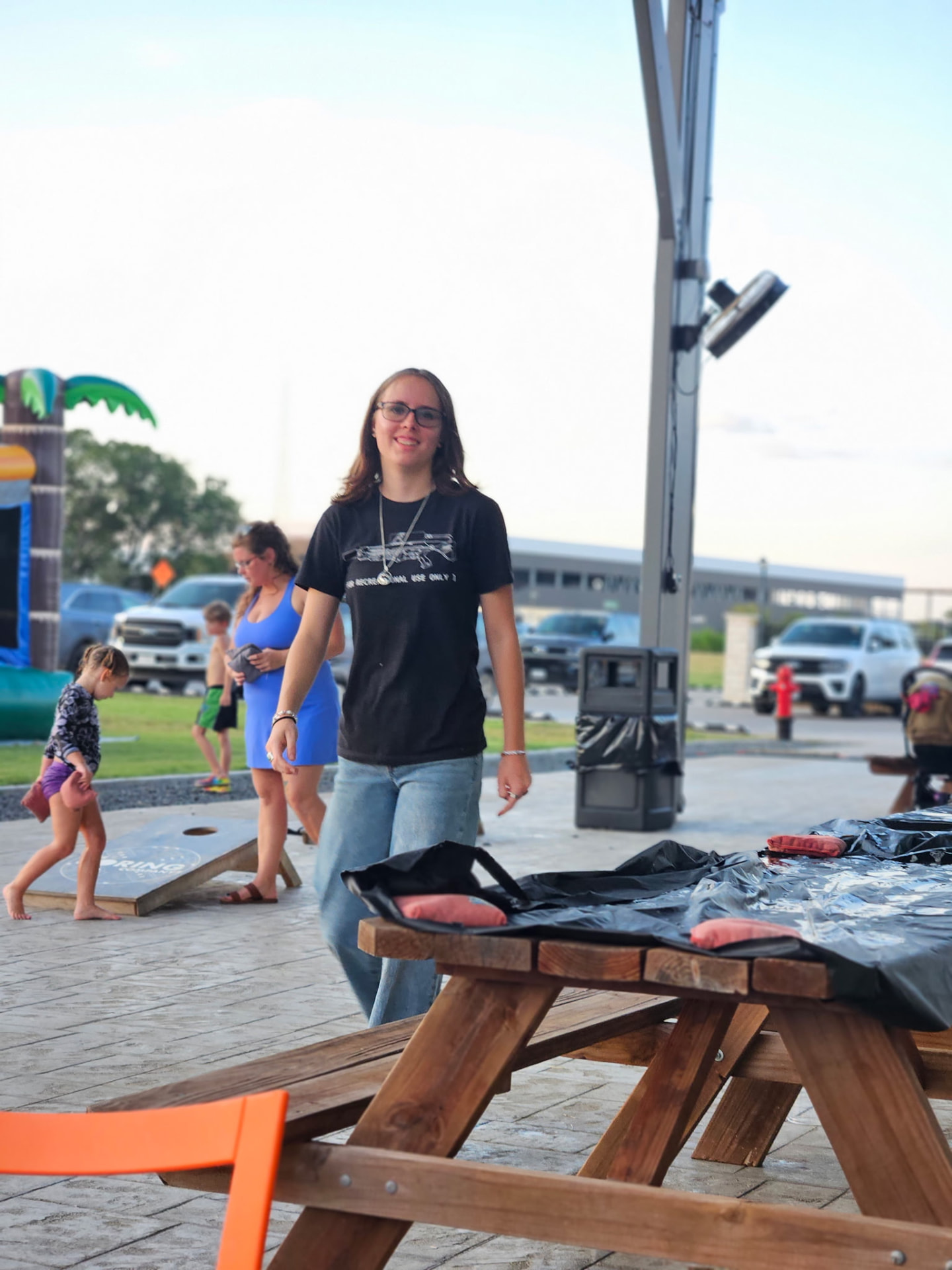 Guest smiling by the cornhole boards on the covered patio