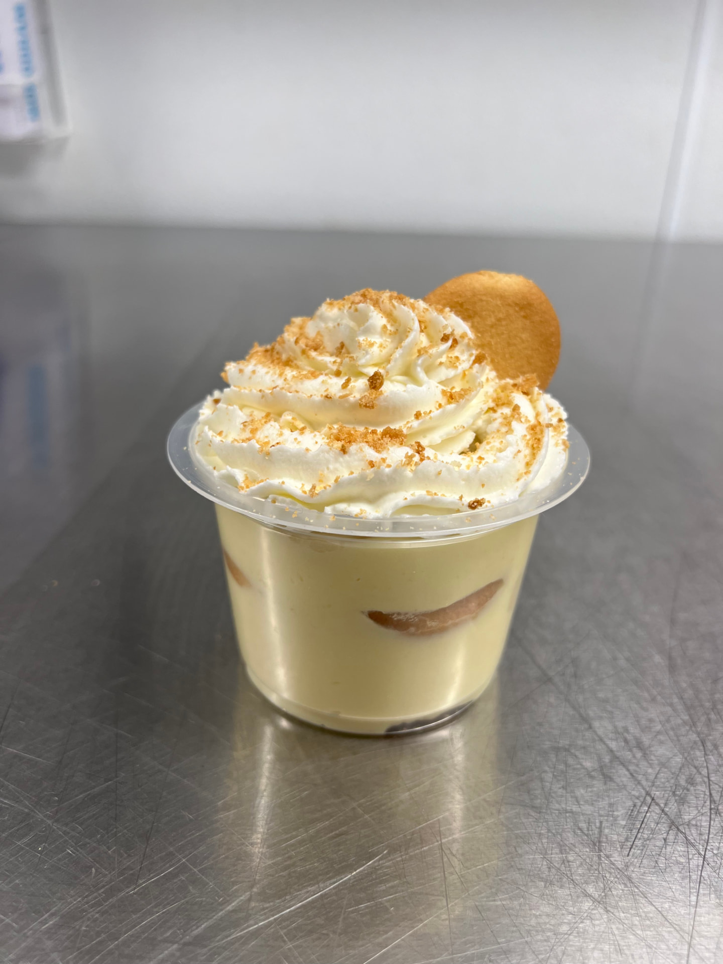 Banana pudding cup topped with whipped cream and a vanilla wafer